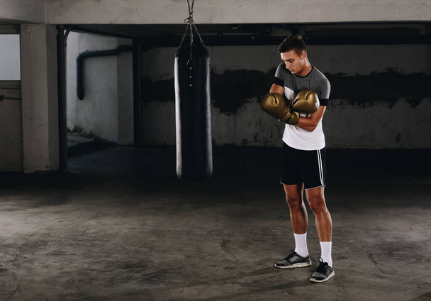 Young sporty Caucasian boxer putting on gloves - Fotó, kép