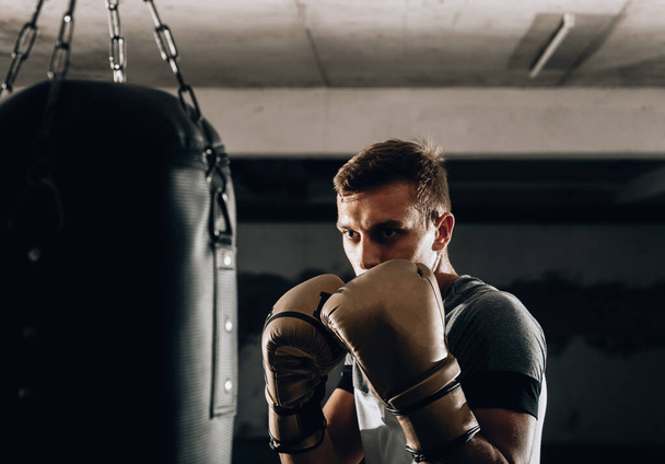 ボクシンググローブでの攻撃的なボクサーパンチバッグ付きトレーニング - 写真・画像