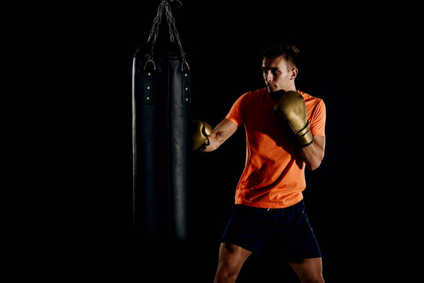 Atletische man in zwarte sportkleding training om te boksen met ponsen b - Foto, afbeelding