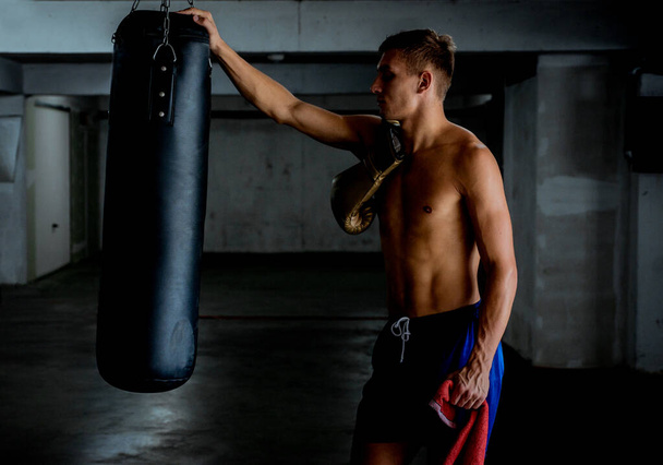 Фитнес-человек стоит рядом с боксерской грушей и готовится к упражнениям
 - Фото, изображение