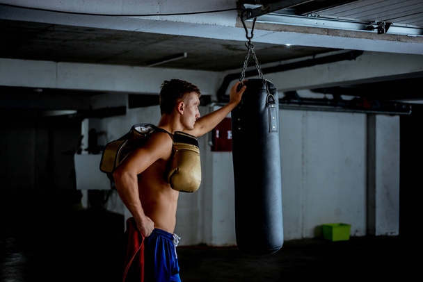 Μυώδης άνδρας με γάντια πυγμαχίας που κάνει διάλειμμα από την άσκηση - Φωτογραφία, εικόνα