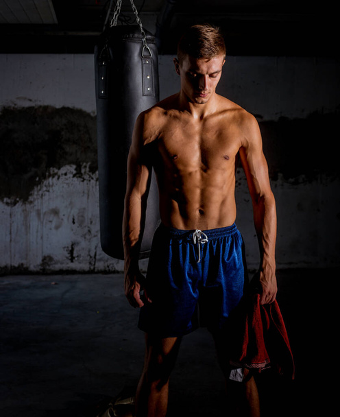 Toalla de joven deportista cerca del saco de boxeo prepararse para el entrenamiento
 - Foto, Imagen