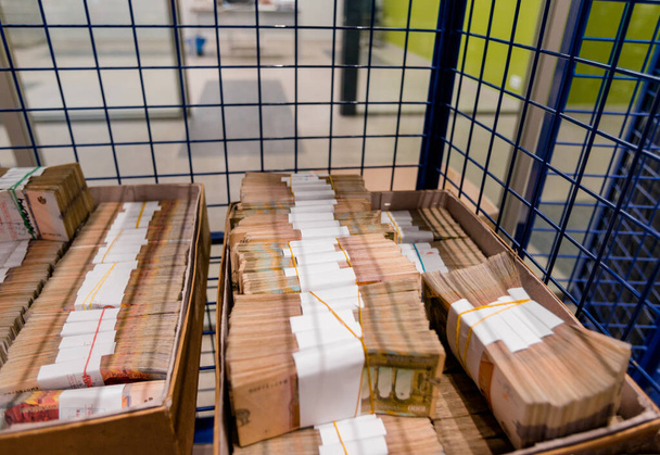 Stacks of banknotes in boxes in metal secured cage - 写真・画像