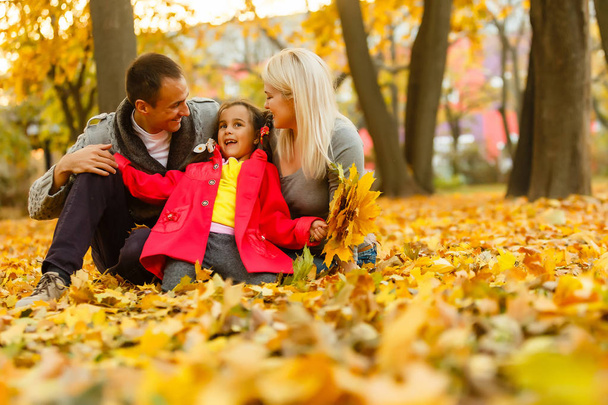 Ευτυχισμένη οικογένεια στηρίζεται σε όμορφο Φθινοπωρινό πάρκο  - Φωτογραφία, εικόνα