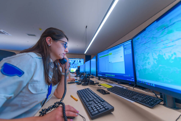 Operadora de guardia de seguridad femenina hablando por teléfono mientras observa el ordenador (ccctv supervisa los monitores. ). - Foto, Imagen