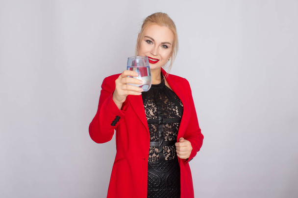 Blonde woman holding water glass over light background - Photo, image