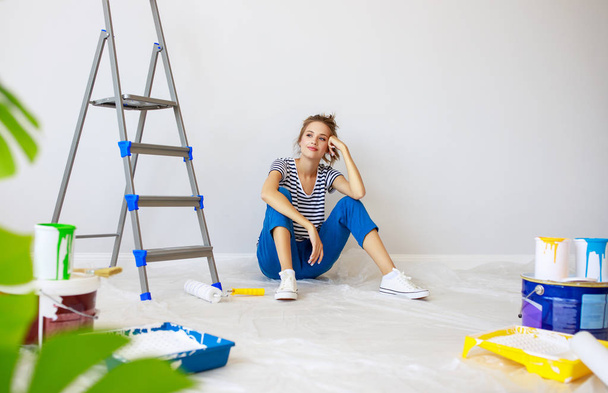 Επισκευή στο διαμέρισμα. Ευτυχισμένη νεαρή γυναίκα ζωγραφίζει τοίχους - Φωτογραφία, εικόνα