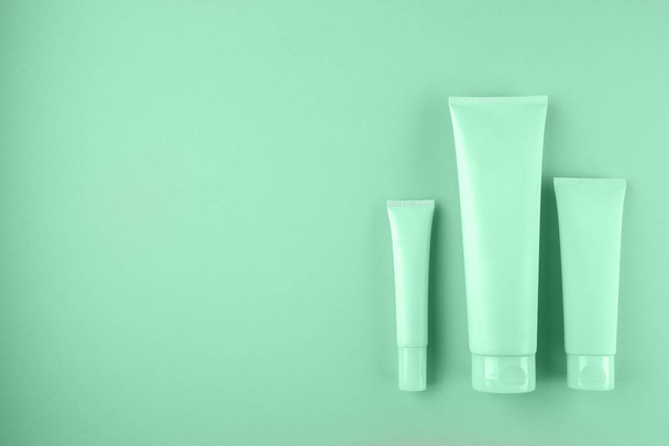 Collection of three cosmetic tubes on mint color background.  - Foto, imagen