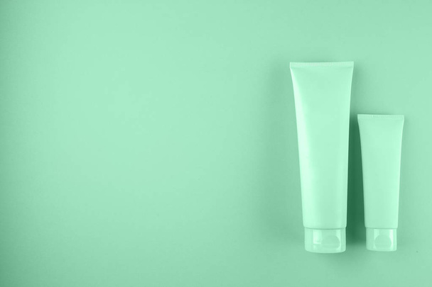 Two cosmetic tubes package on mint color background. - Foto, immagini