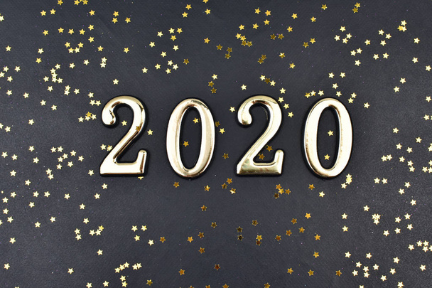 Το 2020 γράφεται σε χρυσούς αριθμούς σε μαύρο φόντο με χρυσά αστέρια. - Φωτογραφία, εικόνα