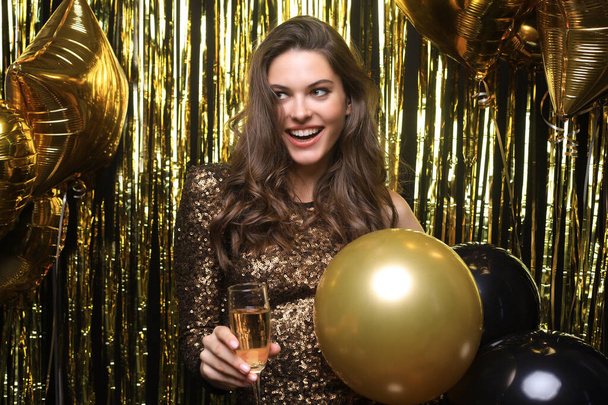 Cheerful woman with balloons laughing on gold background. - Foto, afbeelding