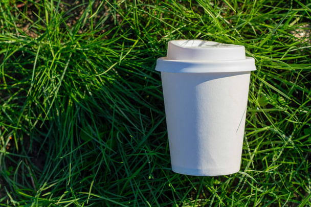 white paper cup with a lid of coffee on the grass - Fotografie, Obrázek