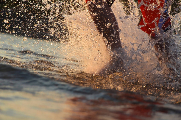 Мальчик бежит по воде, брызгая ногами
 - Фото, изображение