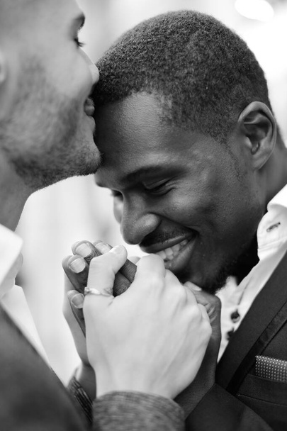 Balck e branco foto de caucasiano homem beijando afro americano menino testa e de mãos dadas
. - Foto, Imagem