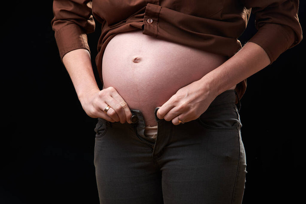 niedogodności w ciąży. ciężarna kobieta nie może zapiąć spodni. ciężar ruchów ciężarnej kobiety - Zdjęcie, obraz