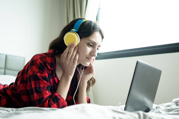 Belle femme qui travaille et écoute de la musique sur un ordinateur portable avec  - Photo, image