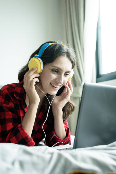 Gyönyörű nő dolgozik, és zenét hallgatni egy laptopon  - Fotó, kép