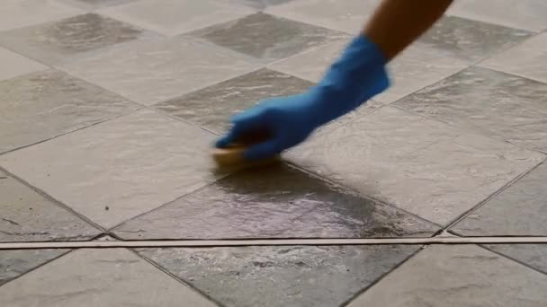 Käsi mies yllään sininen kumi käsineet käytetään muuntaa hangata puhdistus laatta lattialle
. - Materiaali, video