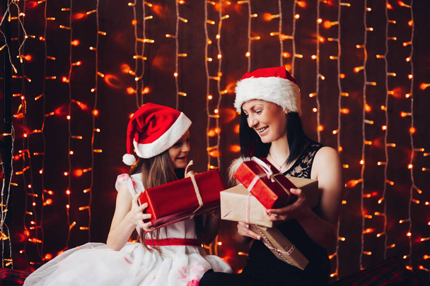 Happy mother with daughter unwrapping Christmas presents. - Photo, Image