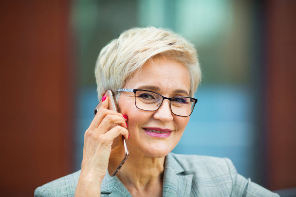 beautiful stylish woman with a short haircut in a suit calls on the phone - Photo, image
