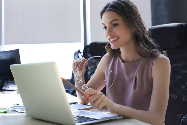 Beautiful business woman in smart casual wear working on laptop in the office - Foto, afbeelding