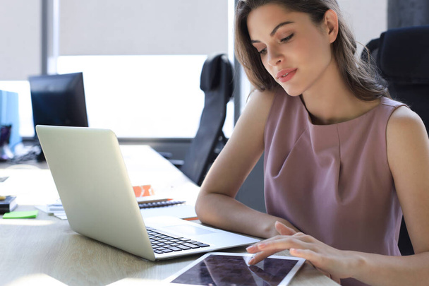 Beautiful business woman in smart casual wear working on laptop in the office - Foto, Imagen