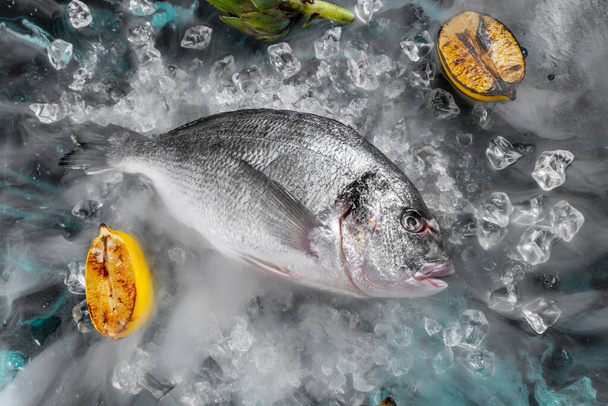 Raw dorada fish with ingredients on dark background - Valokuva, kuva