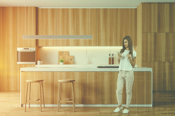 Vrouw in houten keuken met bar - Foto, afbeelding