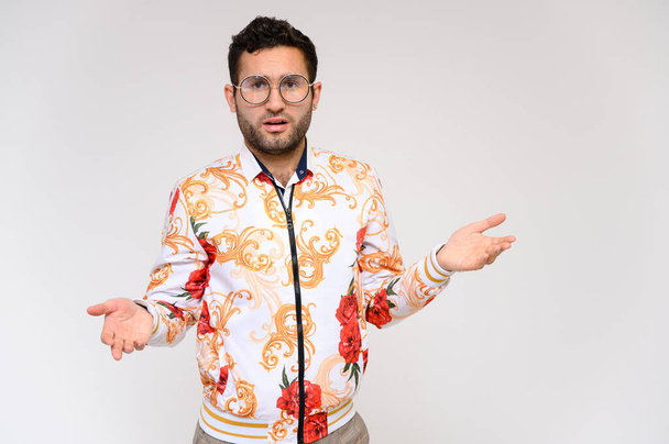 Men's fashion concept. Portrait of a handsome male model showing hands wearing a white floral jacket posing on a white background. Black hair. Close Studio Shot - Φωτογραφία, εικόνα