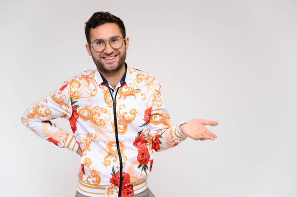Mens fashion concept. Portrait of a handsome male model showing hands wearing a white floral jacket posing on a white background. Black hair. Close Studio Shot - Φωτογραφία, εικόνα