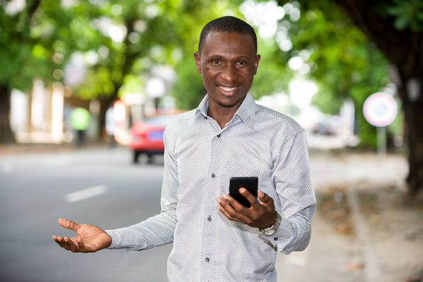 Cep telefonlu, gülümseyen Afrikalı genç bir adamın portresi.. - Fotoğraf, Görsel