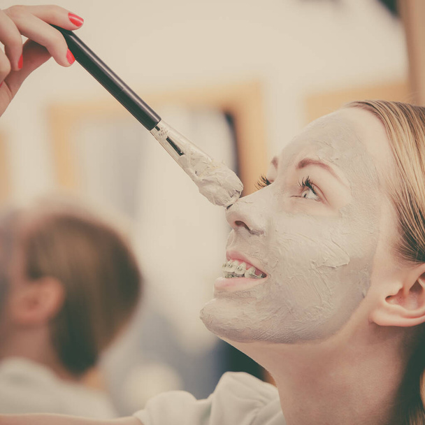 Femme appliquant avec un masque de boue d'argile brosse sur son visage
 - Photo, image
