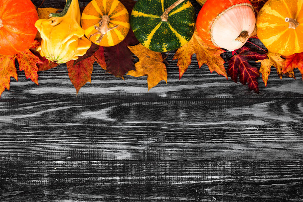 Thanksgiving or Halloween background. Autumn composition. Pumpkins with fall leaves on black wooden table. Flat lay - Foto, imagen