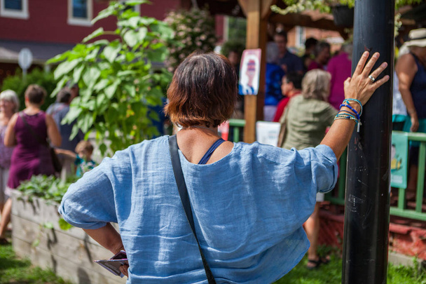 Mladá žena s modrou košilí a modrými náramky se opírá o tyč - Fotografie, Obrázek