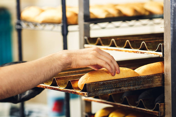 baker puts ciabatta buns on pallets. horizontal photo - Fotografie, Obrázek