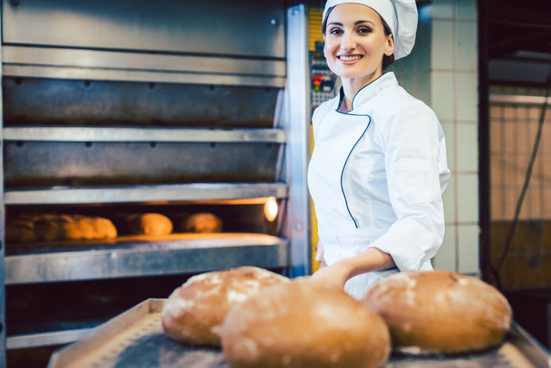 Baker nő mutatja frissen sült kenyeret lapáton - Fotó, kép