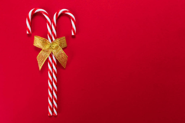 zwei Weihnachtsbonbons mit goldener Schleife auf rotem Hintergrund. Kopierraum. - Foto, Bild