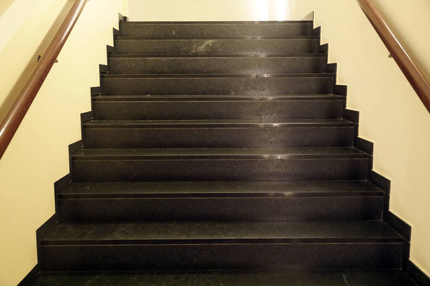 Σκούρο καφέ σκάλες με αντανάκλαση κίτρινες ακτίνες του τεχνητού φωτός - Φωτογραφία, εικόνα
