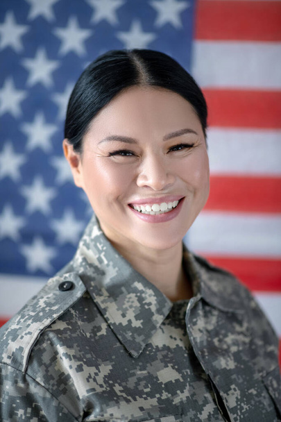 Beaming servicewoman laughing while coming back home - 写真・画像