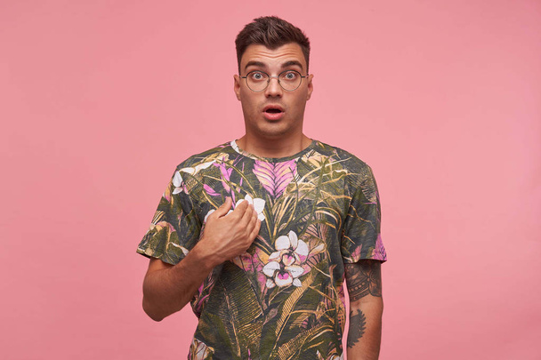 Studio portrét zmateného atraktivního mladého muže ukazujícího na sebe rukou, který vypadá překvapeně na kameru se zvednutým obočím, izolovaný nad růžovým pozadím - Fotografie, Obrázek