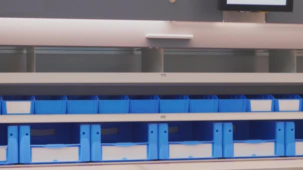 Carrusel vertical automatizado para almacenar componentes en el almacén de almacenamiento. Cajas azules y blancas para piezas de producción moviéndose de arriba abajo. Almacenamiento de documentos en estantes automáticos. Tecnología de automatización para el arreglo en fabricación, tienda, industria
 - Metraje, vídeo