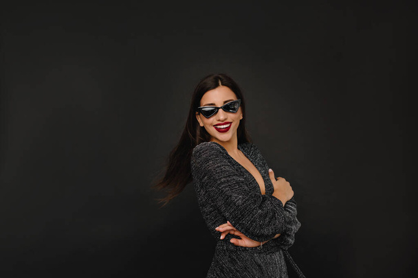 Close-up indoor photo of pretty european woman in sunglasses posing on black background. Dansing, happiness, party - Valokuva, kuva