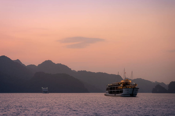 Ha Long Bay in Vietnam tijdens een prachtige zonsondergang met kalme, rustige zeeën. Neergeschoten in het najaar van 2019 van een cruiseschip tour - Foto, afbeelding