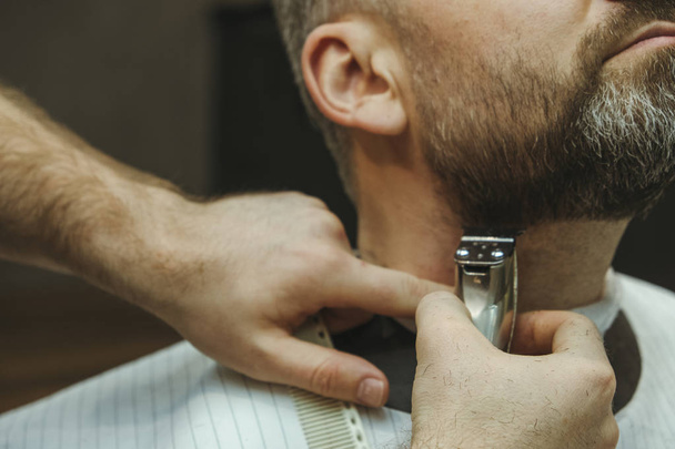 Detalhes de aparar. Barbear uma barba a um cliente numa barbearia
 - Foto, Imagem