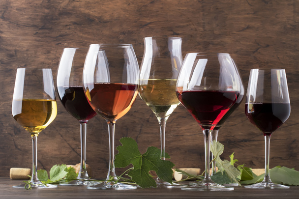 Wine set. Red, white and rose wine in assortment in wineglasses. Wine tasting, vintage wooden background, selective focus, copy space - Foto, Imagen