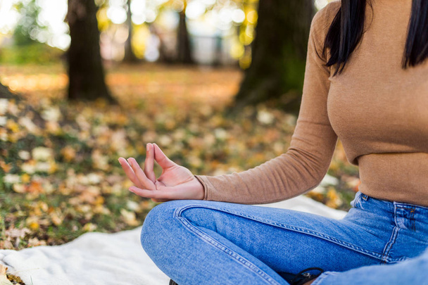 Жінка медитує під час відпочинку і насолоджується восени в парку
. - Фото, зображення