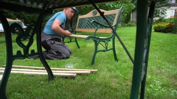 Hombre trabajador desmontar banco retro en partes. Proceso de renovación de mobiliario exterior
 - Imágenes, Vídeo