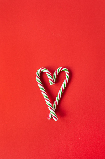 Новорічна / Різдвяна композиція. Символ серця з цукерок тростини на червоному тлі. Плоский простір, вид зверху креативна святкова концепція
. - Фото, зображення