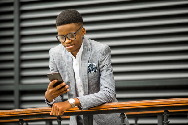beau jeune homme africain en costume et lunettes avec un téléphone dans les mains
 - Photo, image