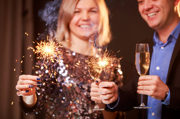 Εικόνα του ευτυχισμένου ζευγαριού με ποτήρια σαμπάνιας και sparklers σε μαύρο φόντο - Φωτογραφία, εικόνα